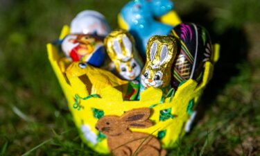 An Easter basket filled with chocolate figures and decorative eggs sits in a garden on March 18