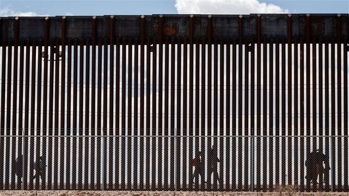 <i>Justin Hamel/Reuters via CNN Newsource</i><br/>Migrants walk along the Mexico-US border after the the Republican-backed Texas law known as SB 4 took effect on March 19.