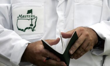 Arnold Palmer looks over his shoulder as he sits with a group of caddies during the 1965 Masters.