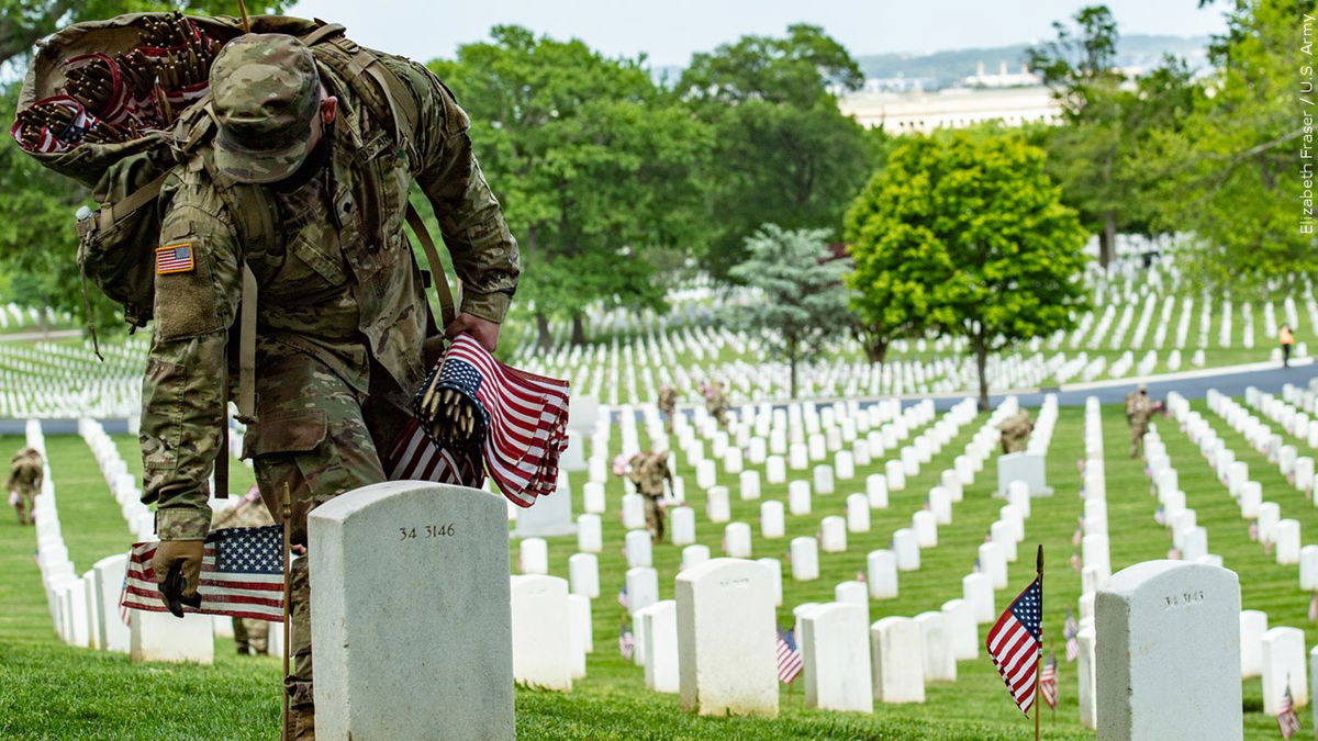 PHOTO: Soldier placing U.S. flags near headstones at Arlington National Cemetery in Virginia, Photo Date: 5/21/2020