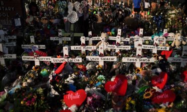 Flowers are piled around crosses with the names of the victims killed in a school shooting as people visit a memorial at Robb Elementary School to pay their respects May 31