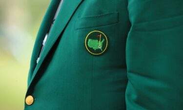 Faldo helps 1997 Masters champion Woods into his green jacket.