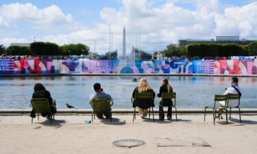 Visitors look at the Eiffel Tower adorned with the Olympic Rings ahead of the Olympic Games in Paris.