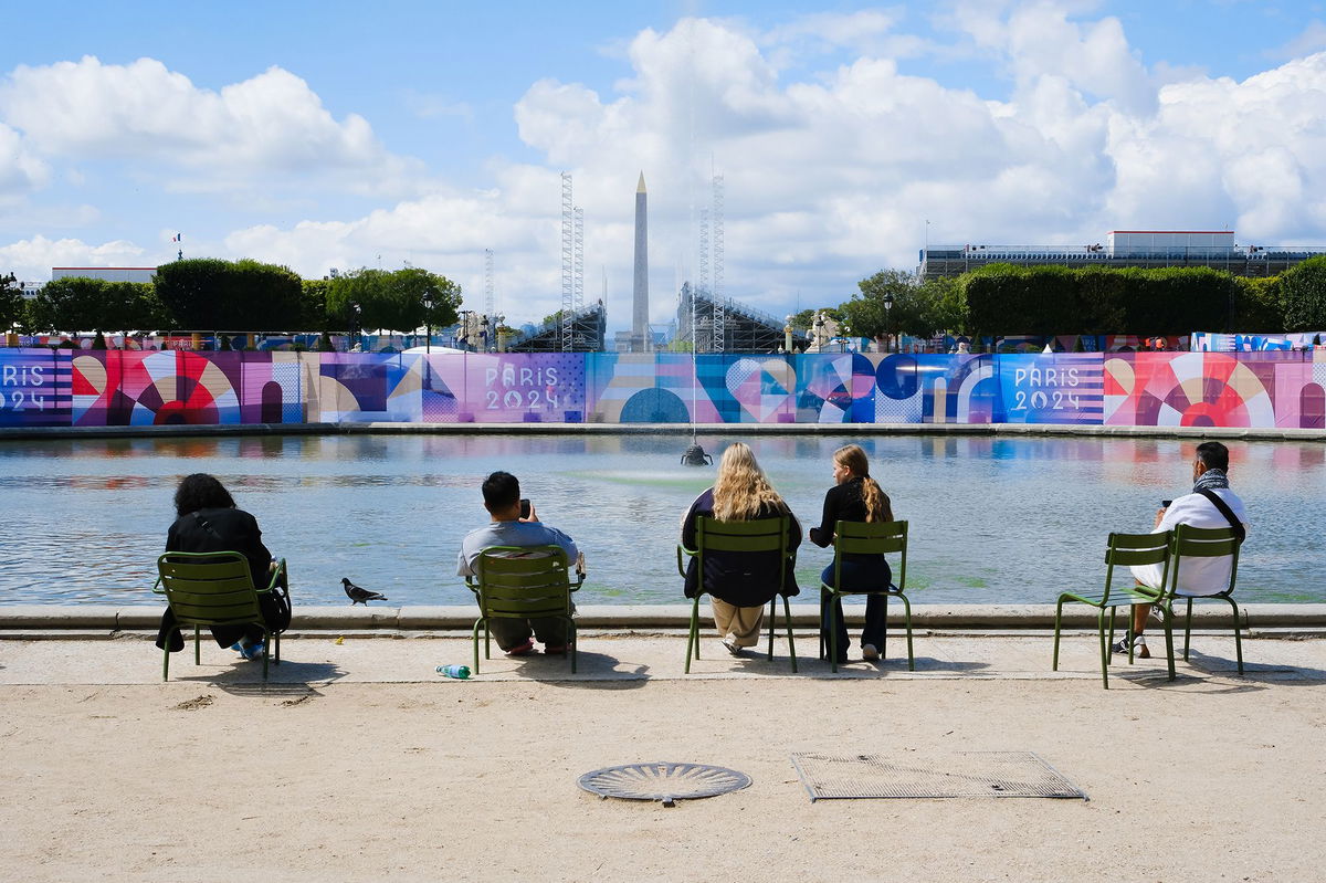 <i>Emmanuel Dunand/AFP/Getty Images via CNN Newsource</i><br/>Visitors look at the Eiffel Tower adorned with the Olympic Rings ahead of the Olympic Games in Paris.