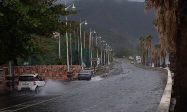 Tourists sit on La Pared beach as Tropical Storm Ernesto whips up surf near Luquillo