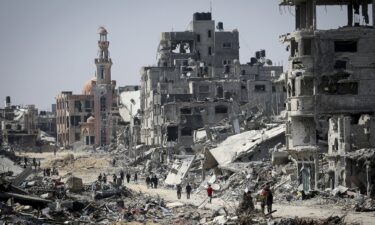 People walk amid the rubble of buildings destroyed during Israeli bombardment in Khan Younis