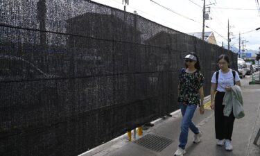 People walk pass the black screen as the city of Fujikawaguchiko built a screen to dissuade tourists from taking photos of Mount Fuji