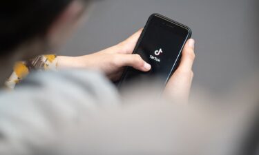 A teenager looks at a smartphone with the TikTok logo displayed. A bipartisan group of 14 attorneys general from across the country filed lawsuits on October 8 against TikTok