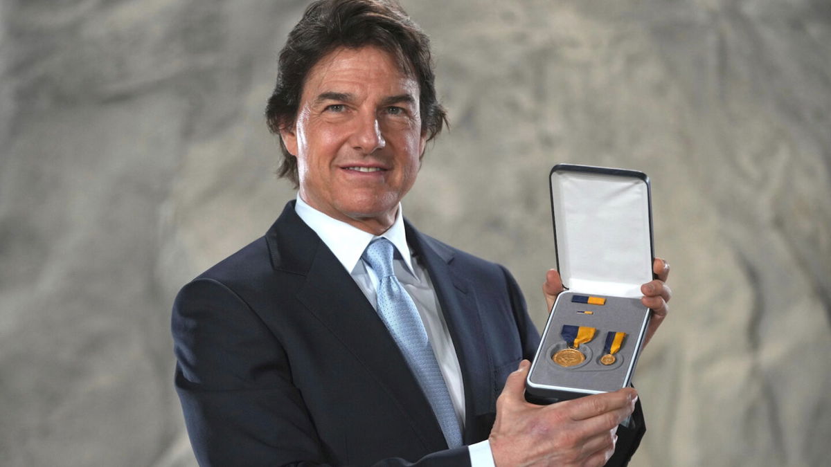 Tom Cruise poses with the Navy Distinguished Public Service Award received from The United States Secretary of the Navy Carlos Del Toro, at the Longcross South Studios, in Runnymede, Surrey, England, Tuesday, Dec. 17, 2024.