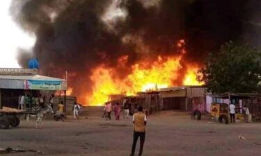 A man stands by as a fire rages in a livestock market area in al-Fasher