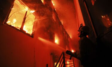 A firefighter works from a deck as the Palisades Fire burns a beach front property in Malibu on January 8.