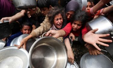 Palestinians wait to receive food cooked by a charity kitchen