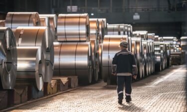 A worker walks past coils of finished steel at the Thyssenkrupp steel mill on March 20 in Duisburg