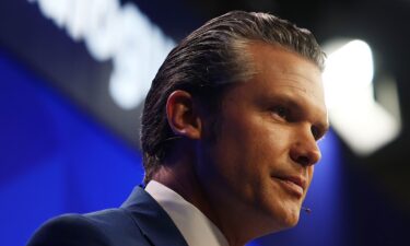 Attendees outside the ballroom watch on a screen as Secretary of Defense Pete Hegseth delivers an address at the Shangri-La Dialogue Summit in Singapore on Saturday