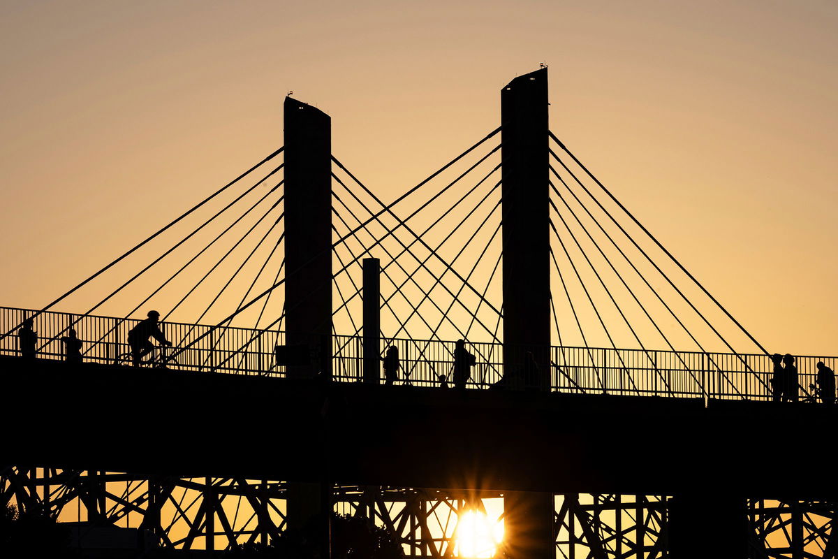 <i>Jon Cherry/AP via CNN Newsource</i><br/>Poeple walk across the Big Four Bridge as the sun sets at Waterfront Park on June 22 in Louisville