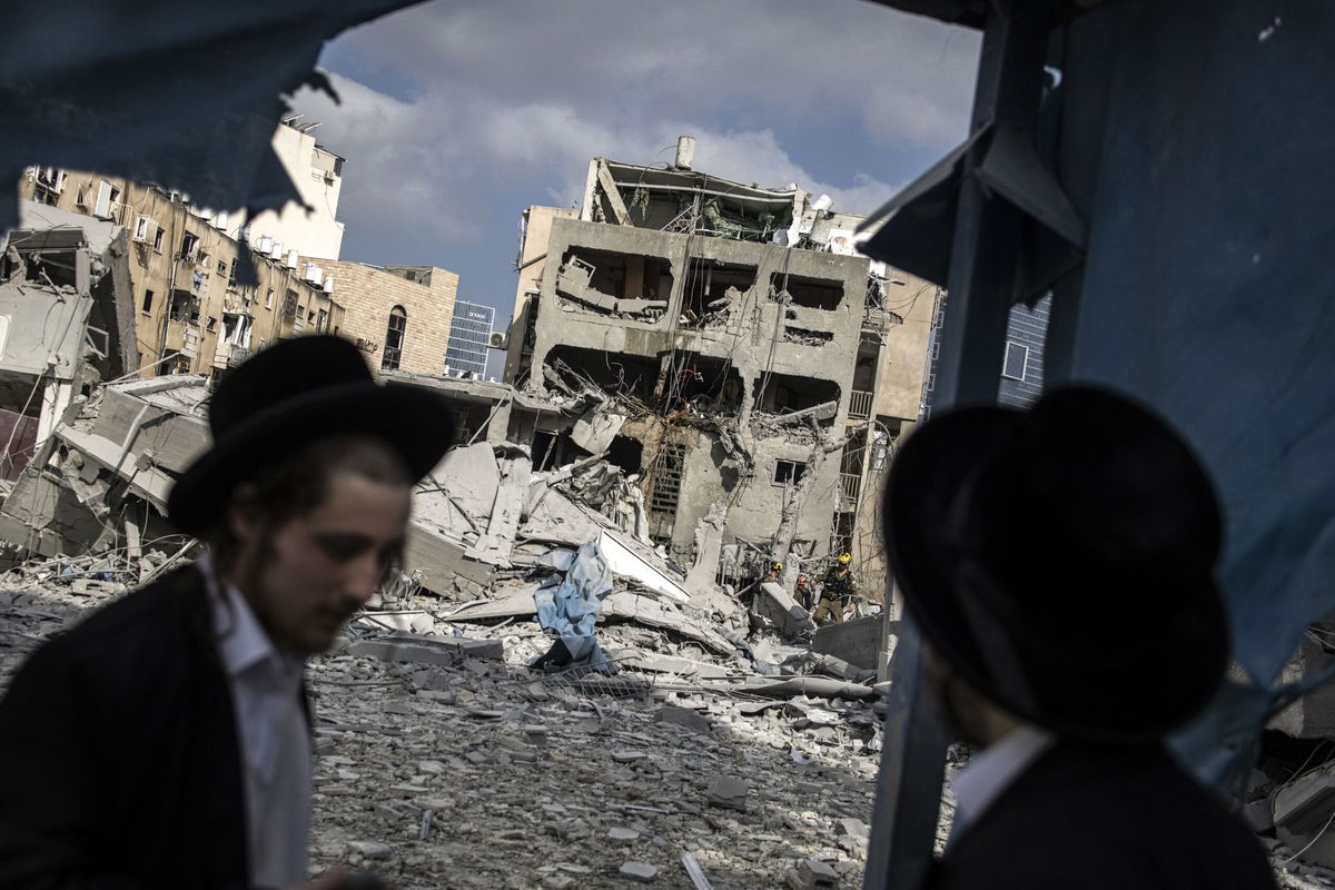 <i>John Wessels/AFP/Getty Images via CNN Newsource</i><br/>Men inspect damage at the site of an Iranian missile strike in Bnei Brak