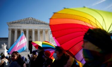 People hold rainbow-colored umbrellas and flags at a demonstration as the US Supreme Court hears arguments over an appeal by President Joe Biden's administration of a lower court's decision upholding a Republican-backed ban in Tennessee on gender-affirming medical care for transgender minors