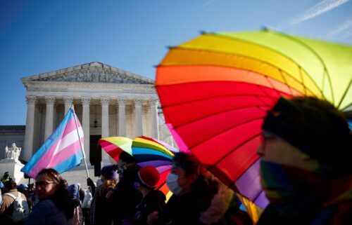 People hold rainbow-colored umbrellas and flags at a demonstration as the US Supreme Court hears arguments over an appeal by President Joe Biden's administration of a lower court's decision upholding a Republican-backed ban in Tennessee on gender-affirming medical care for transgender minors