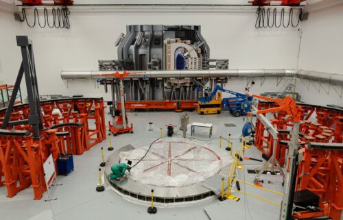 A person works on the cryostat base of the fusion reactor inside the tokamak hall at Commonwealth Fusion Systems in Devens