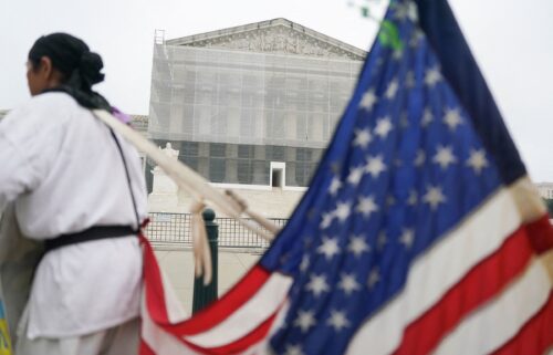 A person stands with a US flag attached to them