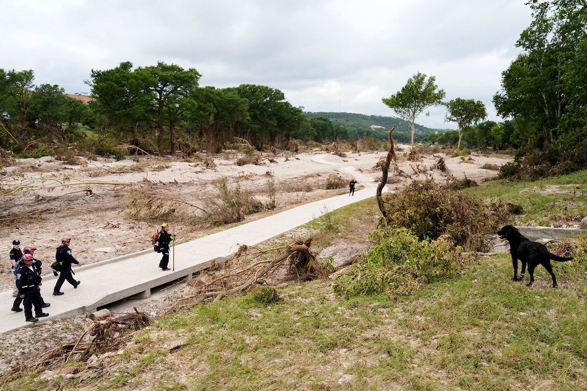 <i>Ashley Landis/AP via CNN Newsource</i><br/>Members of Orange County Task Force One search for missing flood victims in Kerrville