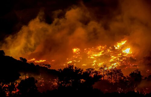 Tourists evacuate a hotel on Crete as wildfires burn.