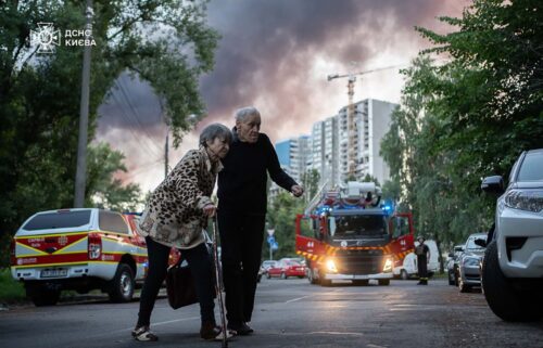 Residents move away from the scene after a Russian airstrike in Kyiv on Friday.
