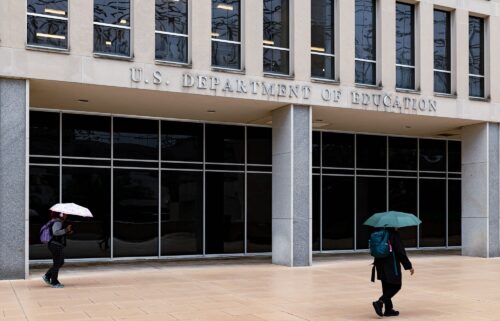 Workers leave the Department of Education building during a rain shower in Washington