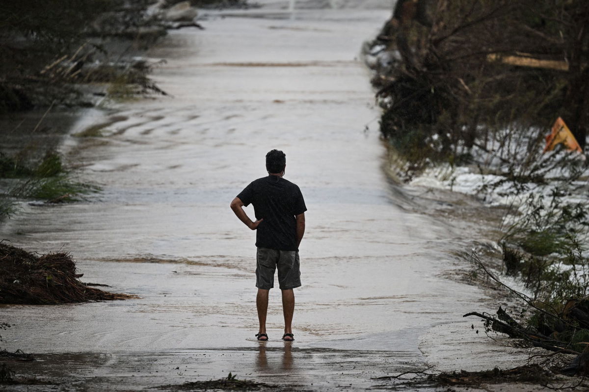<i>Ronaldo Schemidt/AFP/Getty Images via CNN Newsource</i><br/>A man looks at a damaged road after severe flash flooding that occurred during the July 4 holiday weekend