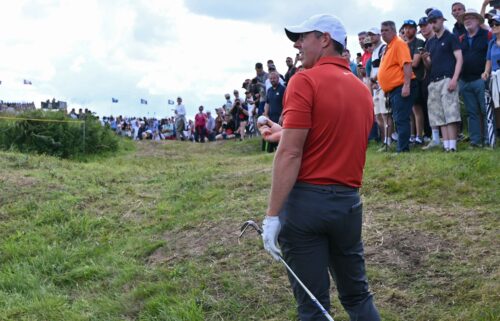 Rory McIlroy reacts after unearthing an old golf ball as he plays his own ball from the rough on the 11th hole at the 153rd Open Championship in Northern Ireland.