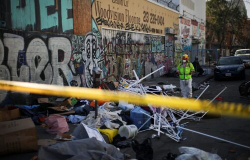 Stockton Police officers watch as inhabitants of a homeless encampment on an island on White Slough move their possessions onto a levee along Trinity Parkway near McAuliffe Road in north Stockton
