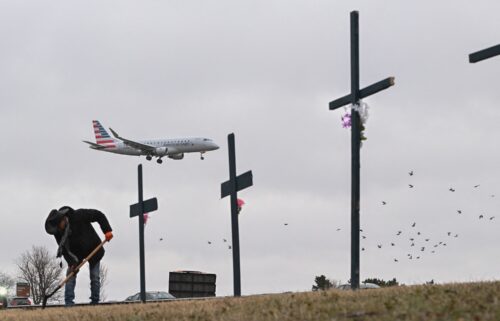 A plane lands behind a memorial to those killed in the midair collision at Reagan National Airport in Arlington