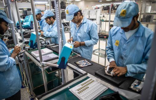 Employees work on a mobile phone assembly line in Noida