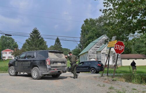 Police officers block the street leading to where two Pennsylvania state troopers were shot on August 7