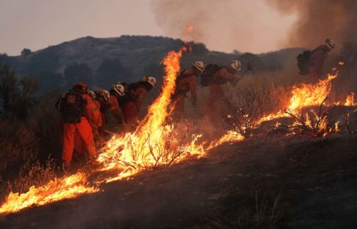 A resident rides a golf cart as he exits his property while the Canyon Fire burns on Thursday in Halsey Canyon
