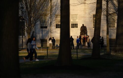 People gather to take photos with the John Harvard Statue at Harvard University on April 17 in Cambridge