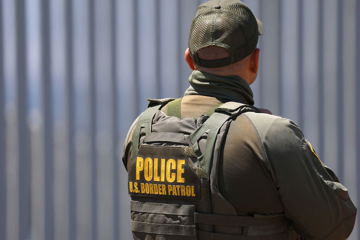 <i>Kevin Carter/Getty Images via CNN Newsource</i><br/>A US Customs and Border Protection Border Patrol agent stands in front of the US-Mexico border wall in Imperial Beach