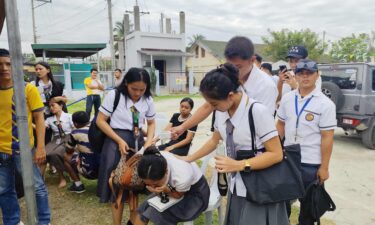 Two women walk past a damaged house after a strong earthquake in Davao City